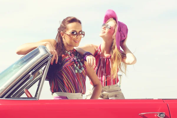 Beautiful ladies with sun glasses posing in a vintage retro car — Stock Photo, Image