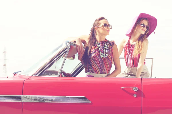 Hermosas damas con gafas de sol posando en un coche retro vintage — Foto de Stock