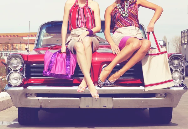 Beautiful ladies with sun glasses posing in a vintage retro car