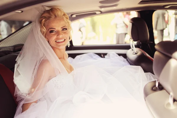 Novia sonriendo desde un coche de lujo — Foto de Stock