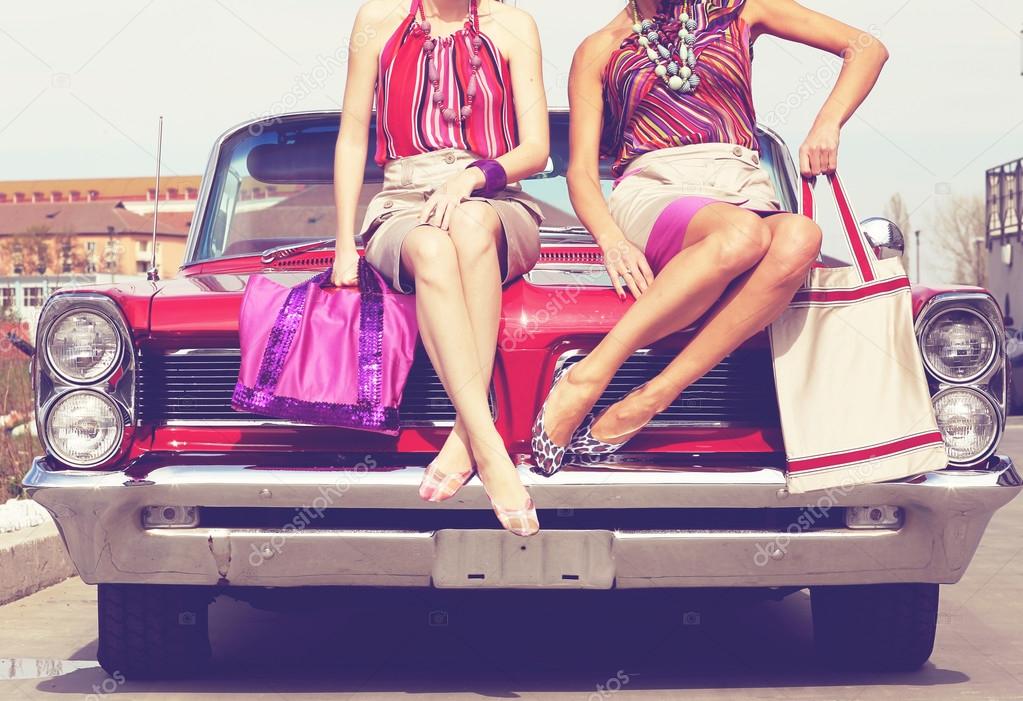 Beautiful ladies with sun glasses posing in a vintage retro car
