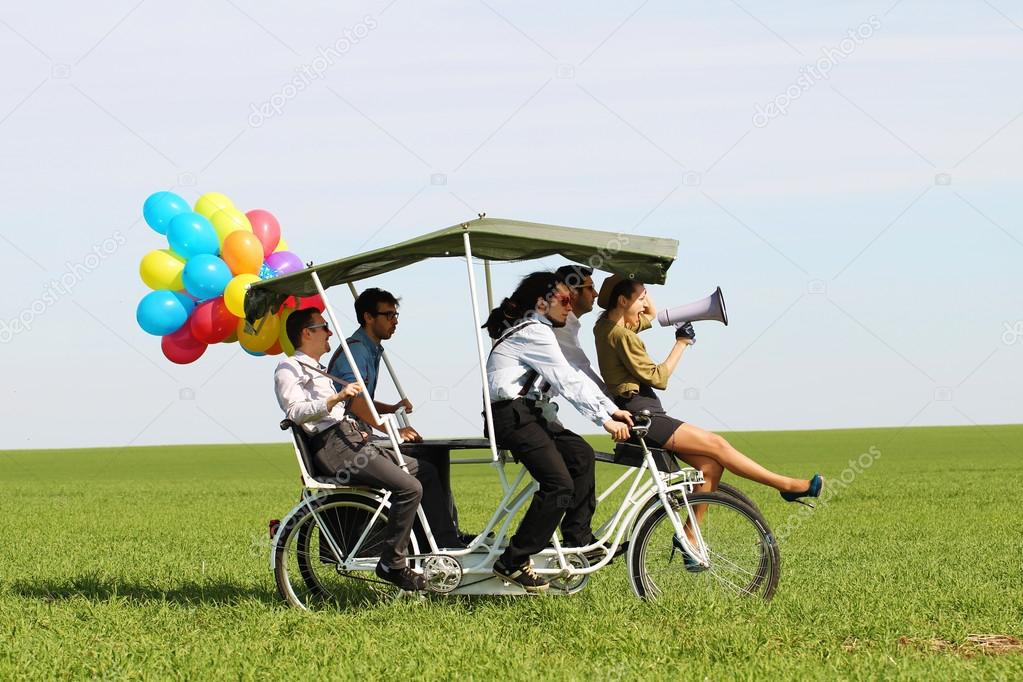 woman leading 4 guys on a quad bike on a green field