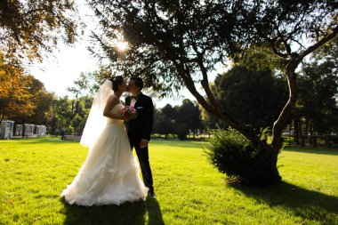 Şık gelin ve damat düğün günü dışarıda birlikte poz veriyorlar.