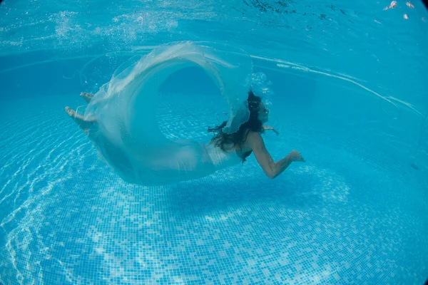 Женщина под водой плавает, одетая в свадебное платье — стоковое фото