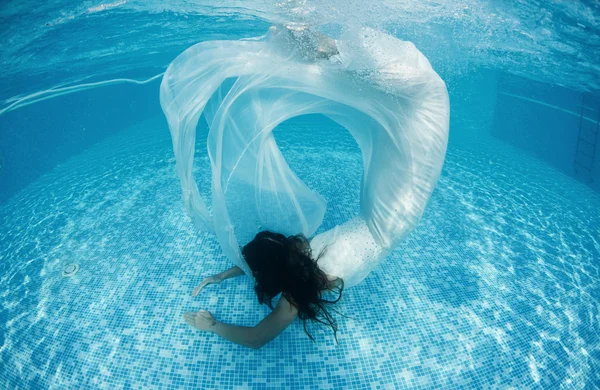 Женщина под водой плавает, одетая в свадебное платье — стоковое фото