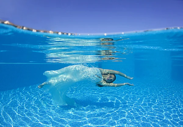 Woman underwater swimming wearing her wedding dress — Stock Photo, Image