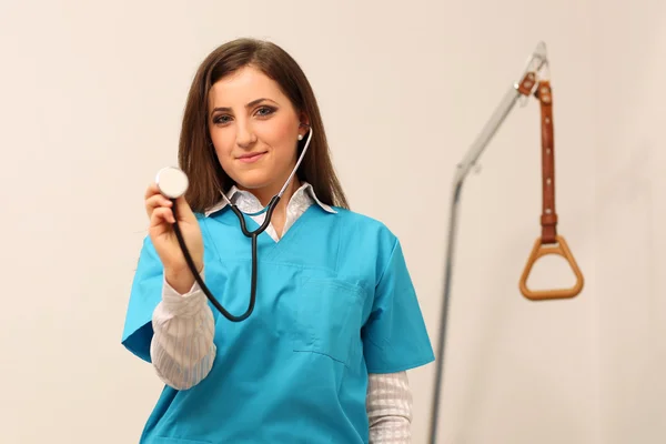 Ženský lékař, usmívající se stetoskopem v rukou — Stock fotografie