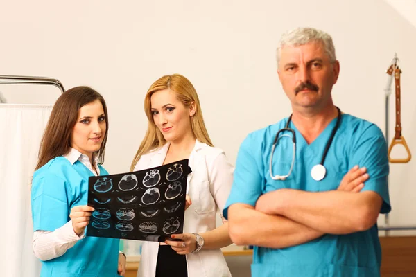 Läkare med två sjuksköterskor kontrollera radiografi — Stockfoto