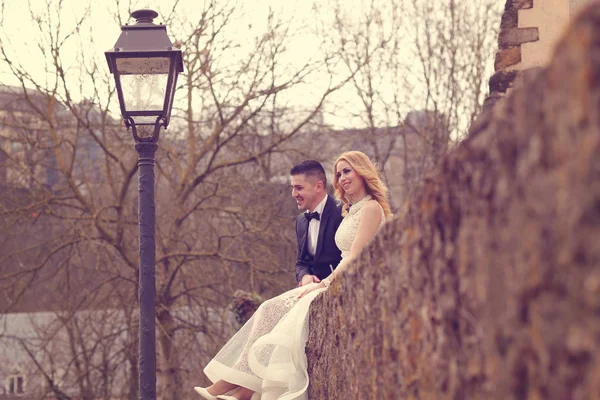 Sposa e sposo seduti su un muro — Foto Stock