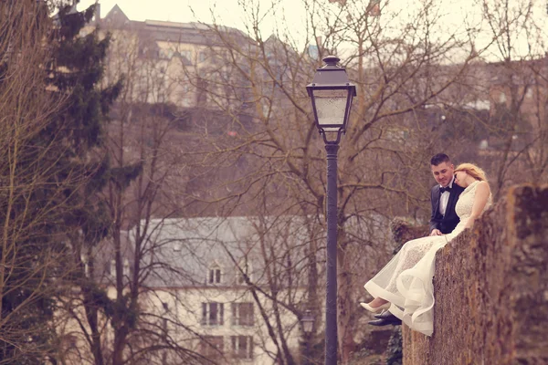 Bride and groom sitting on a wall — Stock Photo, Image