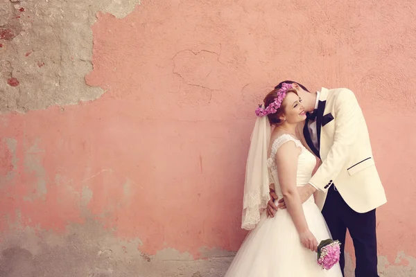 Bruid en bruidegom omarmen in de buurt van muur — Stockfoto