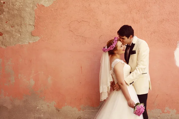 Sposa e sposo abbracciando vicino al muro — Foto Stock