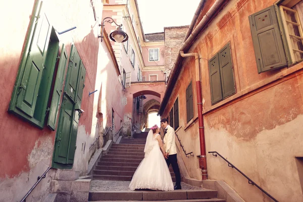 Bride and groom walking in old city — Stock Photo, Image