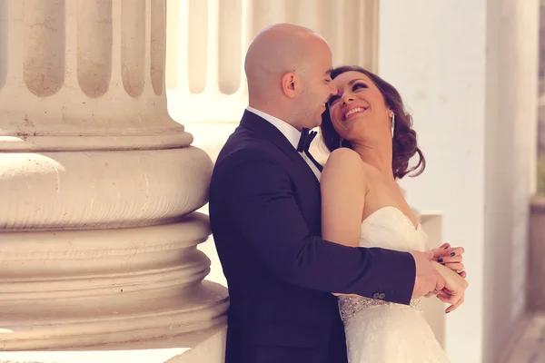 Novia y novio abrazando cerca de columnas — Foto de Stock