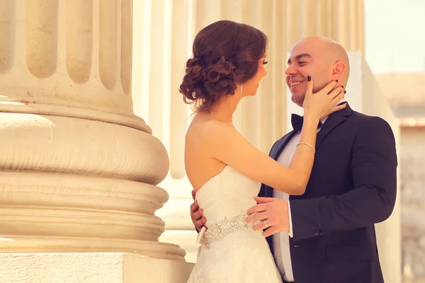 Novia y novio abrazando cerca de columnas —  Fotos de Stock