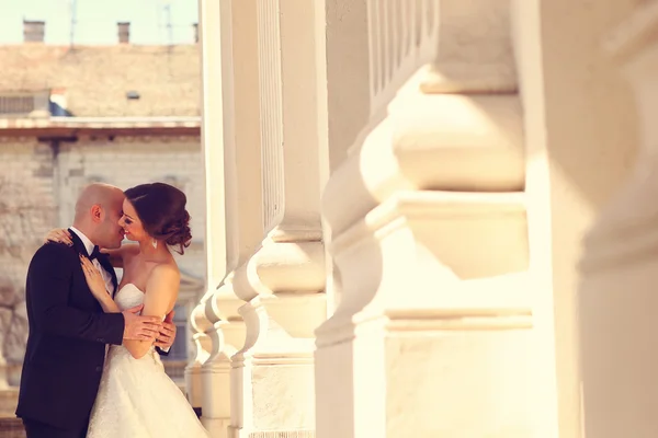 Bride and groom embracing near columns — Stock Photo, Image