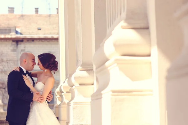 Novia y novio abrazando cerca de columnas —  Fotos de Stock