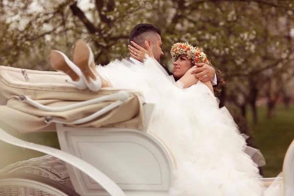 Bride and groom sitting in a white carriage