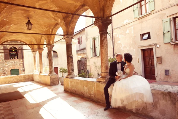 Жених и невеста сидят возле старого здания — стоковое фото
