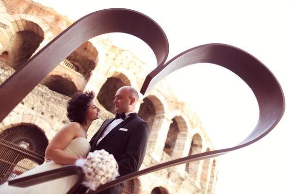 Bride and groom near heart shaped sculpture — Stock Photo, Image