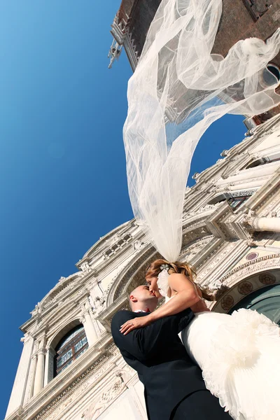 Noiva e noivo beijando na frente da igreja — Fotografia de Stock