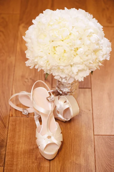 与新娘的鞋子在木地板上的美丽婚礼花束 — 图库照片