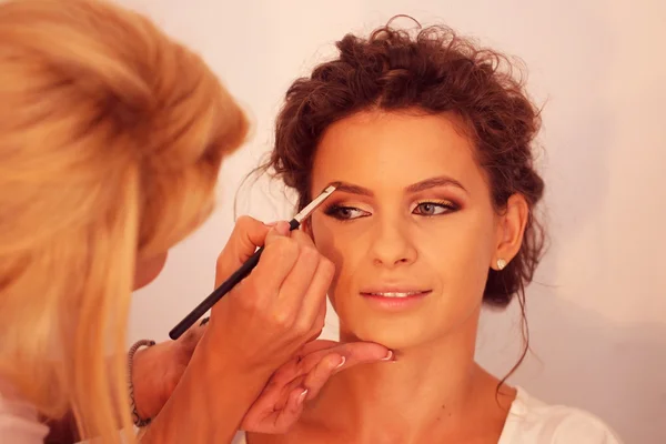 Giovane bella sposa applicare il trucco di nozze da make-up artist — Foto Stock