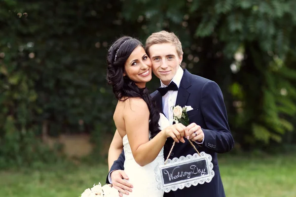 Красивая невеста и жених с табличкой "День свадьбы" — стоковое фото