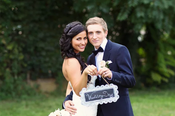 Bela noiva e noivo segurando "Dia do casamento" sinal — Fotografia de Stock