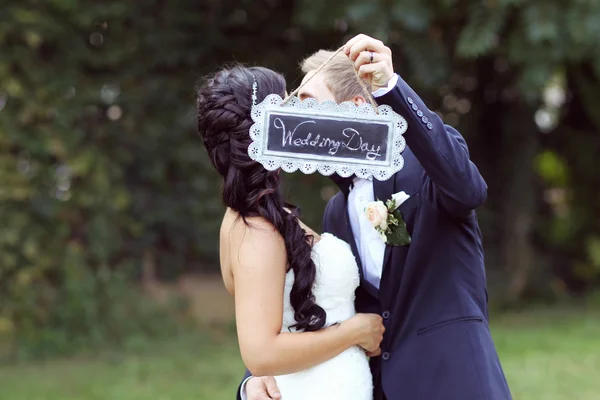 Vackra bruden och brudgummen med "Bröllopsdag" skylt — Stockfoto
