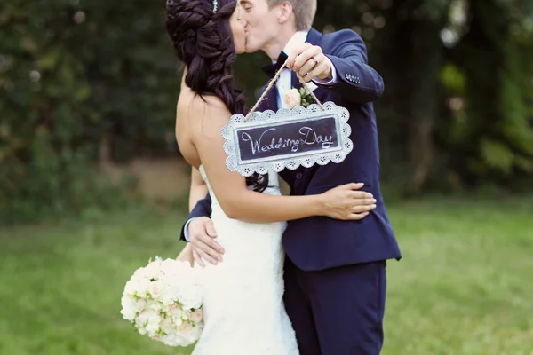 Hermosa novia y novio celebración de "Día de la boda" signo — Foto de Stock