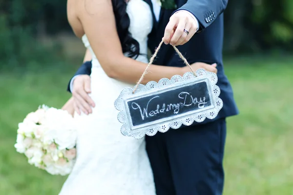 Hermosa novia y novio celebración de "Día de la boda" signo — Foto de Stock