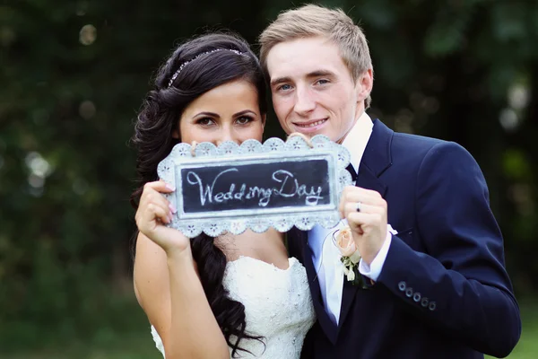 Bela noiva e noivo segurando "Dia do casamento" sinal — Fotografia de Stock