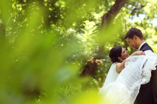 Lyckliga brudparet embracing i park — Stockfoto