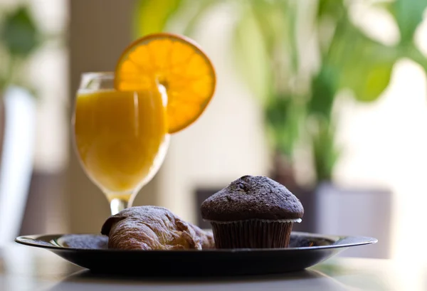 Leckere Muffins und Croissant mit Orangensaft — Stockfoto