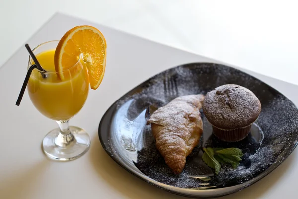 Delicious muffin and croissant with orange juice — Stock Photo, Image