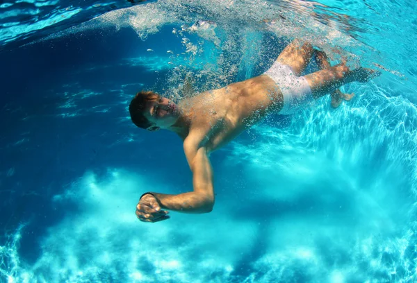 Sexig kille dykning i poolen under vattnet — Stockfoto