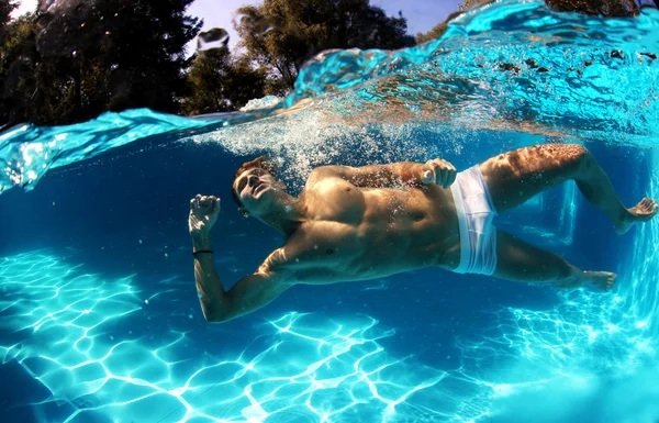 Sexy guy diving in pool underwater — Stock Photo, Image