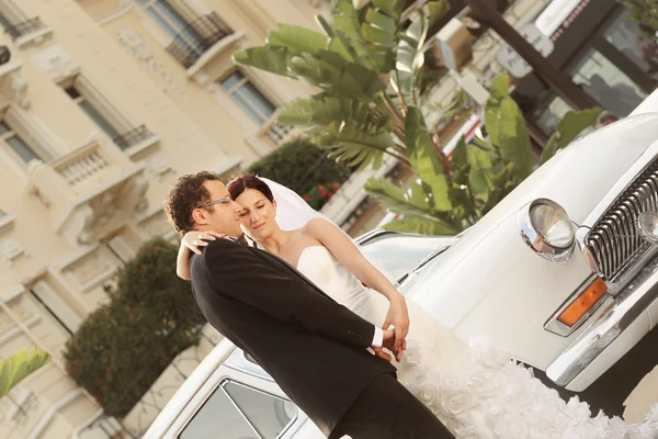 Noivo e noiva posando perto de um carro retro — Fotografia de Stock