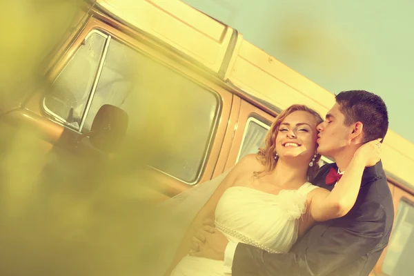 Bruden och brudgummen med en retro buss — Stockfoto