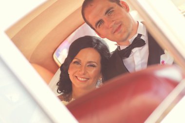 Güzel gelin ve damat arabaya gülümseyen