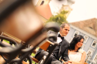 Şehir meydanında bir bankta oturmuş güzel gelin Çift