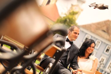 Şehir meydanında bir bankta oturmuş güzel gelin Çift