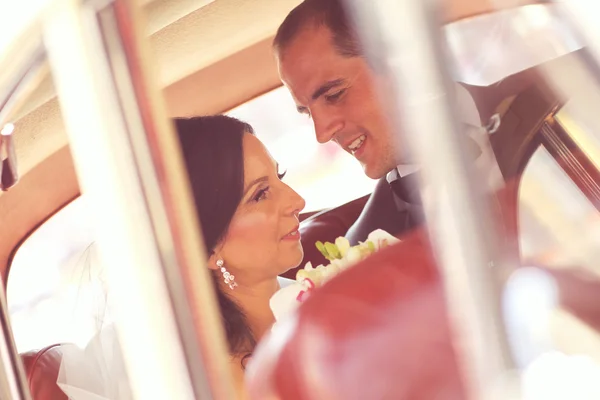 Gyönyörű menyasszony és a vőlegény mosolyog az autó — Stock Fotó
