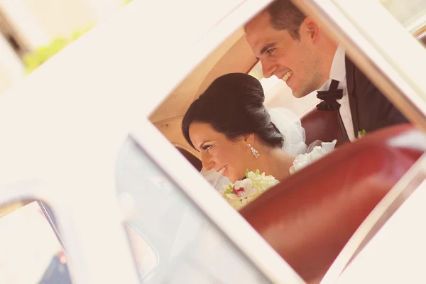 Gyönyörű menyasszony és a vőlegény mosolyog az autó — Stock Fotó