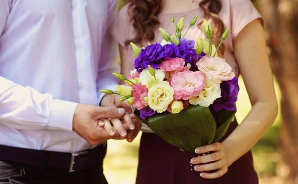 Beautiful bridal couple embracing in park and holding bouquet — Stock Photo, Image