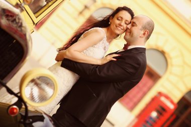 Güzel gelin ve damat klasik otomobil kucaklayan