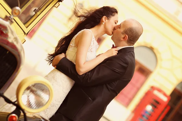 Vackra bruden och brudgummen omfattar nära veteranbil — Stockfoto