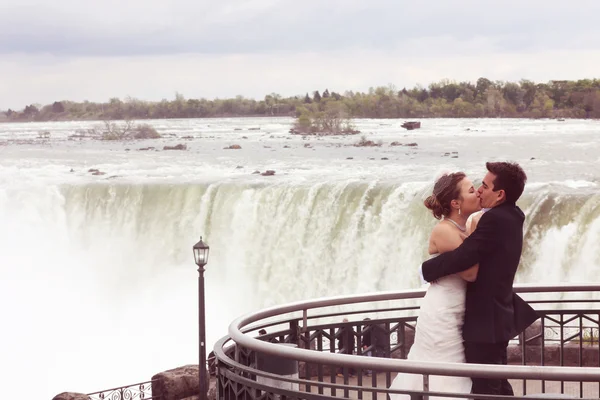 Bride and groom embracing near waterfall — Stock Photo, Image