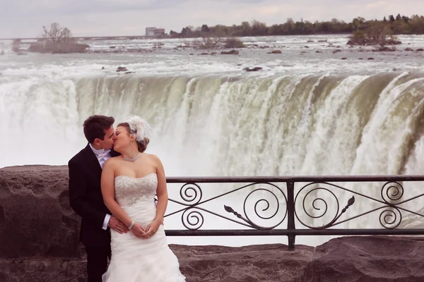 Novia y novio abrazando cerca de la cascada — Foto de Stock